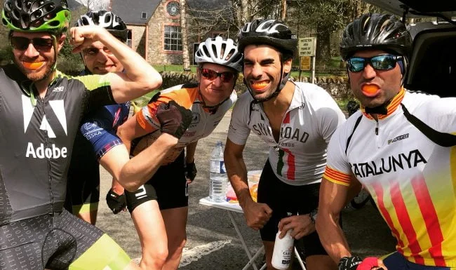 A group of five happy cyclists pull faces and show off their muscles at a refreshment stop on a Skinny Tyres Ltd fully supported road cycling holiday in Scotland.
