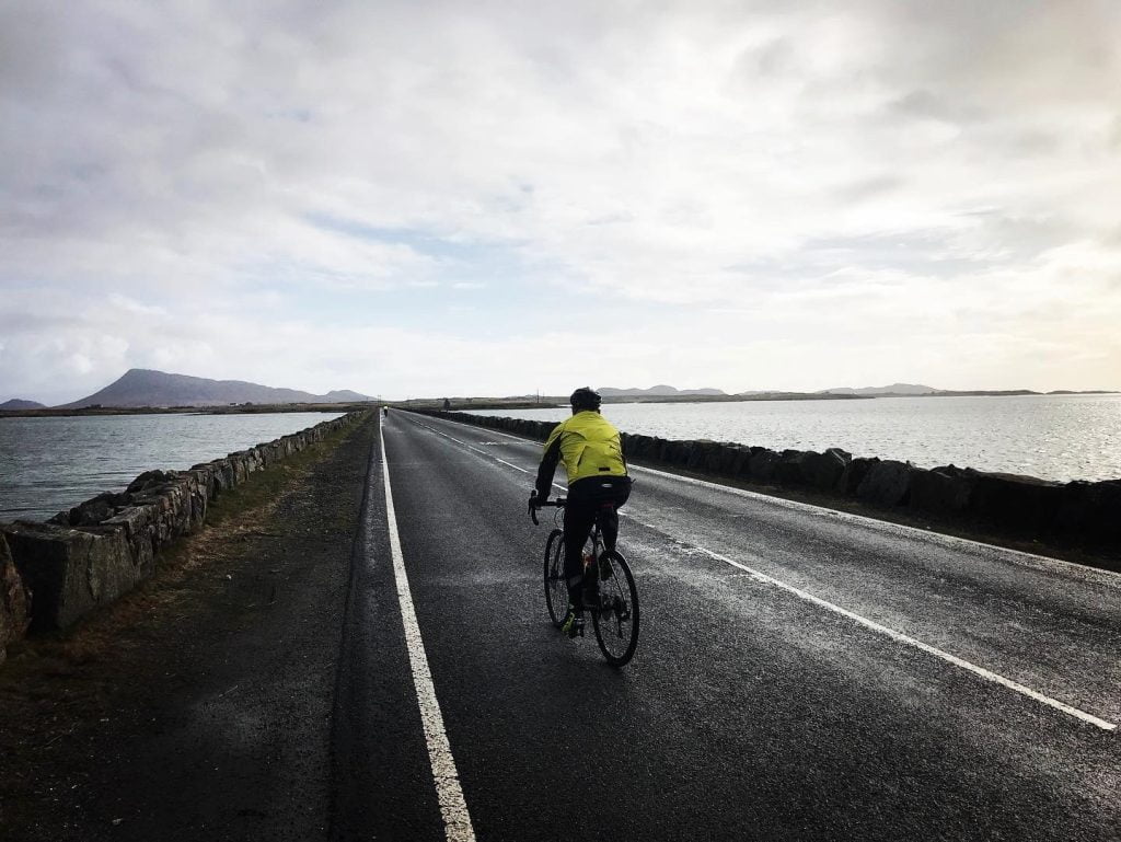 A cyclist on the Hebridean Way crossing a causeway between Benbecula and North Uist NCN 780