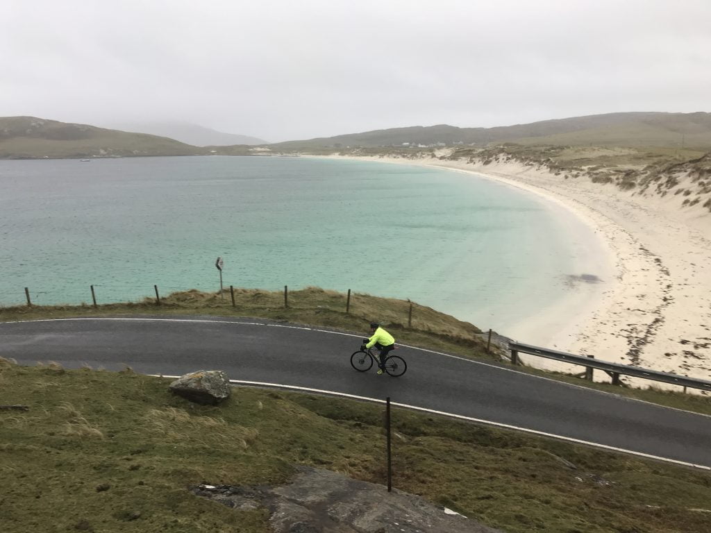 A rider passing by the beautiful beach on Vatersay which marks the start of the Hebridean Way