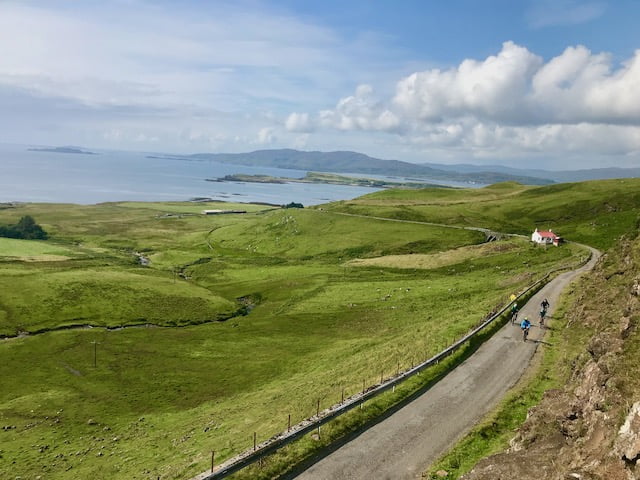 Cyclists on a climb on the West Coast of Scotland, looking over the Atlantic Ocean