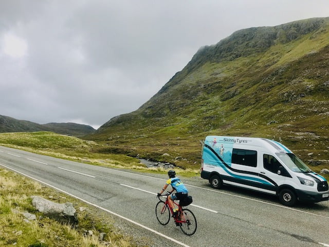 A cyclist rides past a Skinny Tyres support van at the top of the climb up to Clisham on the Hebridean Way - Harris