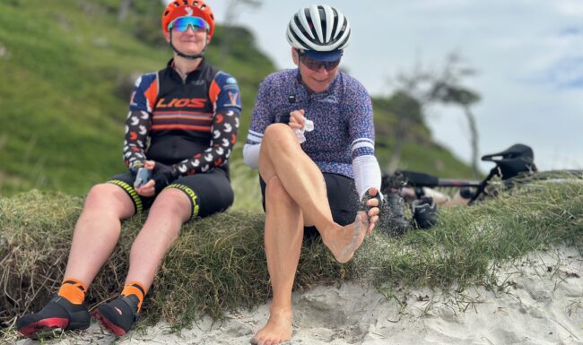 Two Cyclists sitting on the beach at Calgary Bay on the Isle of Mull after paddling in the sea.