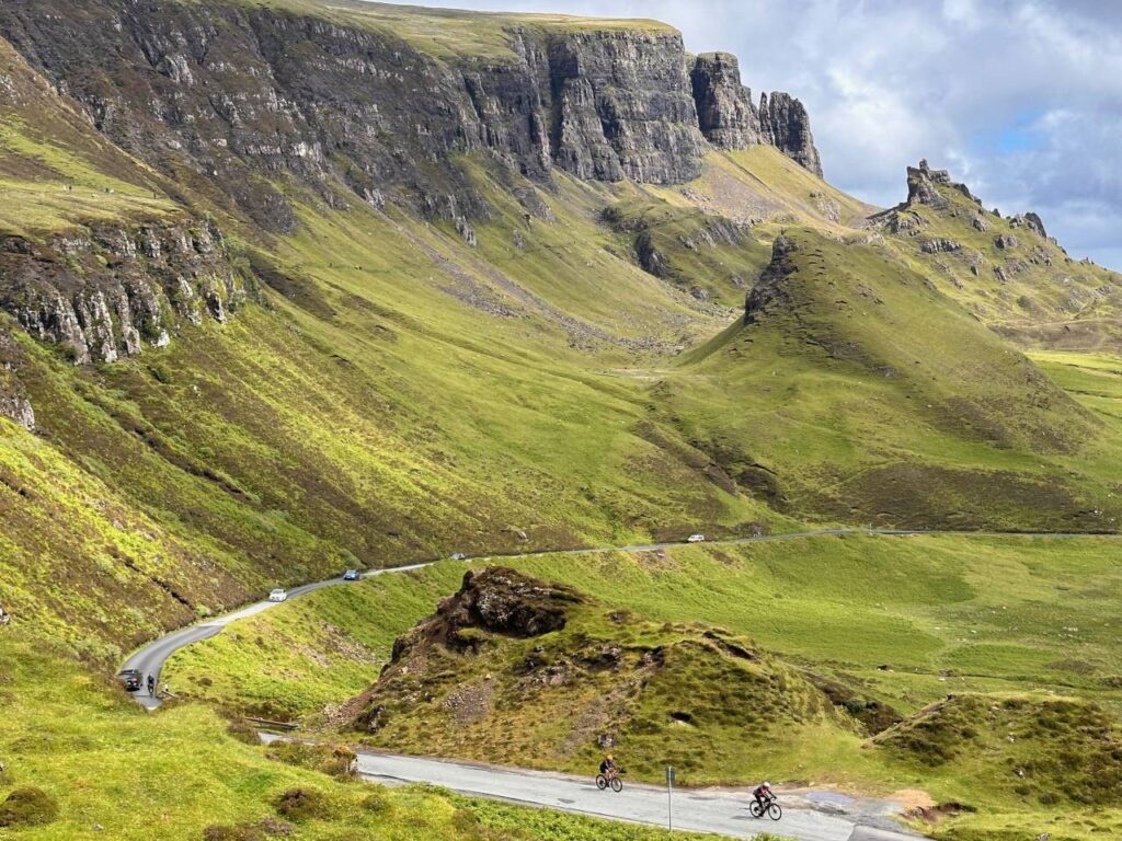 Two cyclists on a Skinny Tyres fully supported road cycling holiday in Scotland pass The Quiraing on the Isle of Skye. A passion and pride for Scotland.