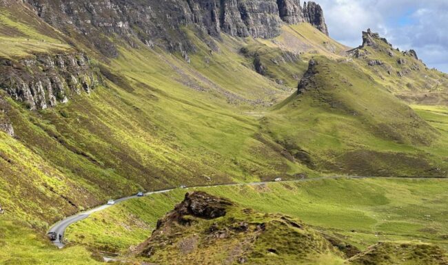 Two cyclists on a Skinny Tyres fully supported road cycling holiday in Scotland pass The Quiraing on the Isle of Skye. A passion and pride for Scotland.