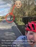 A young cyclist takes a photo of themselves with their dad struggling to keep up in the back ground.