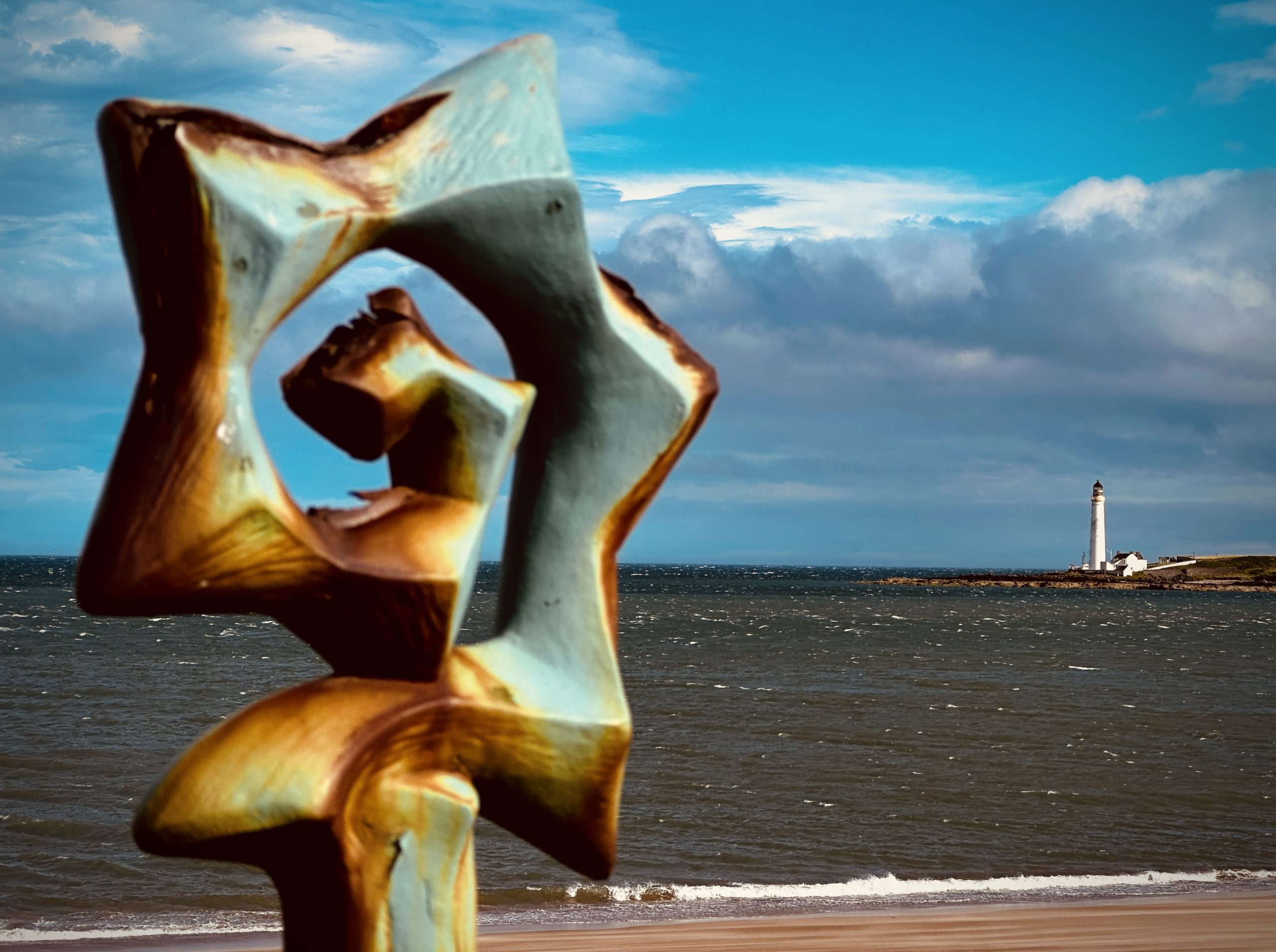 A view from the promenade looking across the sand of Montrose beach to a lighthouse