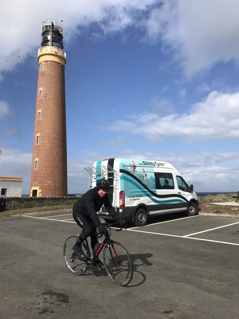 A cyclist rides past the Skinny Tyres support van at the Butt of Lewis