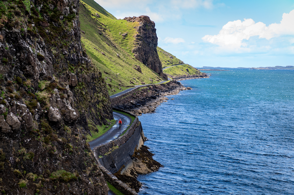A cyclist riding along a single track road on te Isle of Mull with the sea to their left