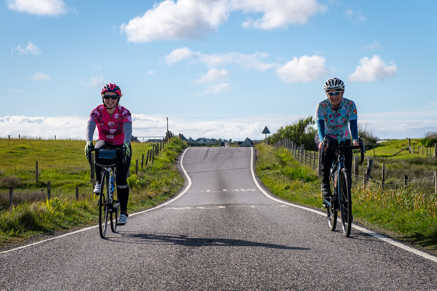 Two women cycling side by side along a single track road