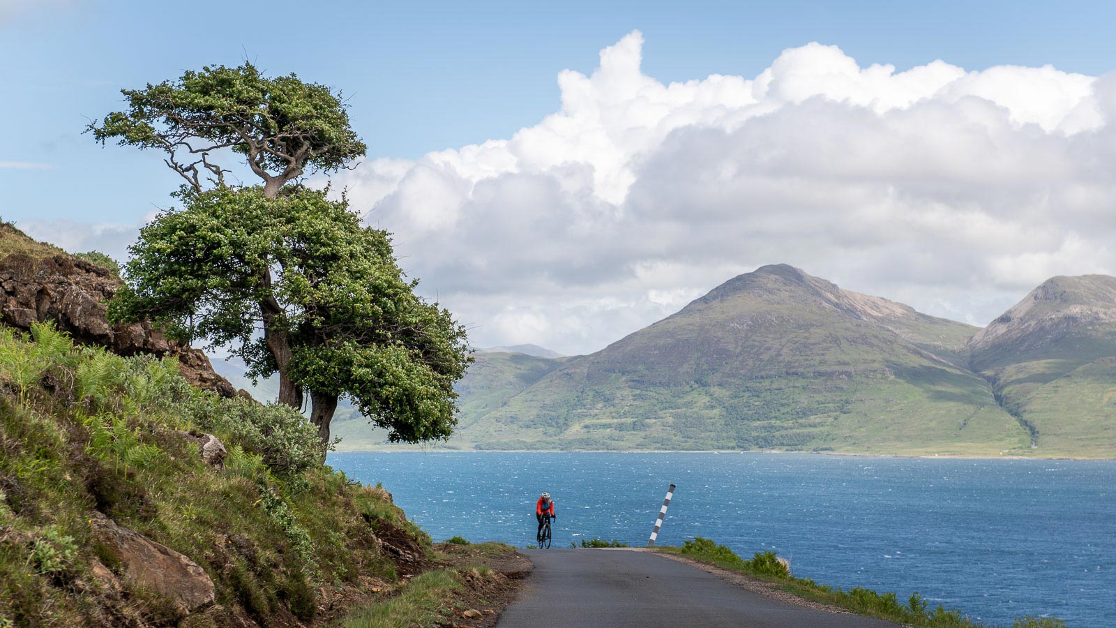 A lone woman cyclist is riding along the northern shores of Loch na Keal on the Scottish Hebridean Island of Mull